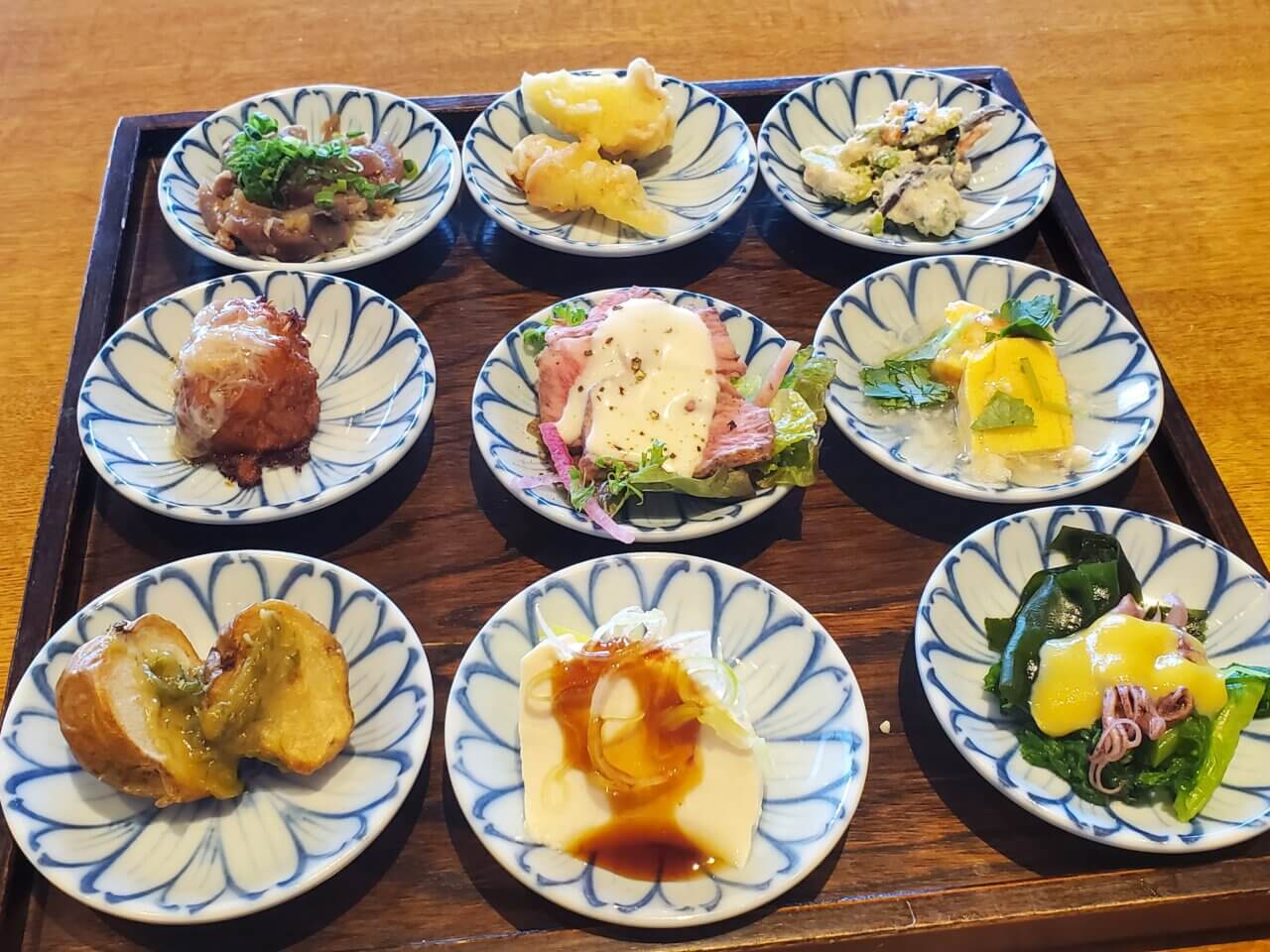 小さな和皿に盛り付けられた9種類の前菜が並んでいる様子。色とりどりの食材が目を引く華やかな盛り付け。