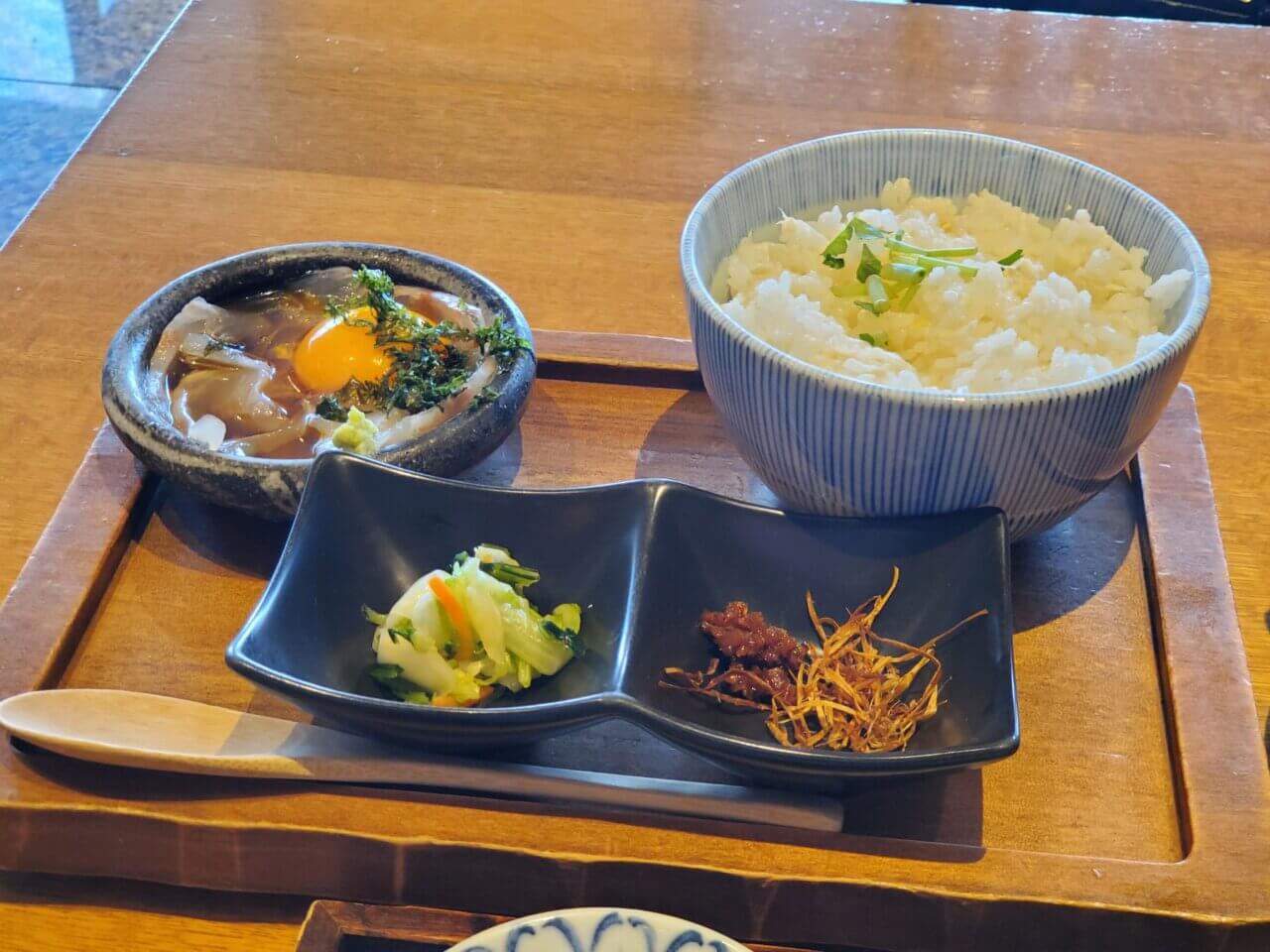 鯛のお刺身、鯛めしと薬味、お新香がセットになったお膳。黒いポットにはお茶漬け用の出汁が入っている。上品な盛り付け。