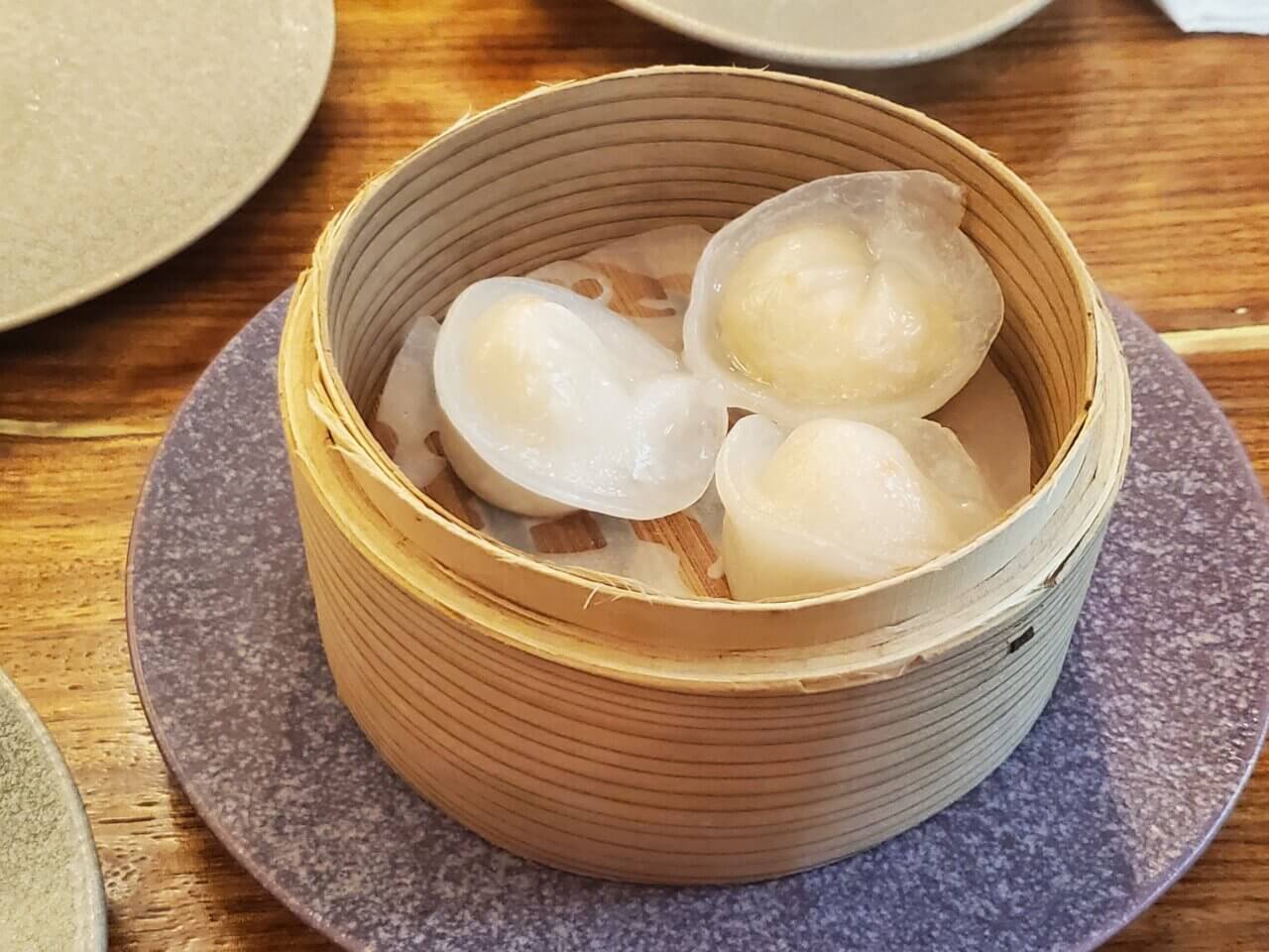 透明感のある皮で包んだホタテの蒸し餃子が竹製の蒸籠に並んでいる写真。