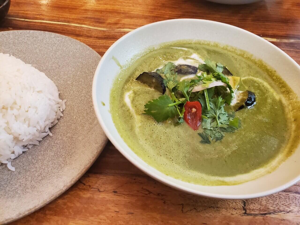 鶏肉となす、筍入りのグリーンカレーとタイ米がセットで盛られた写真。パクチーがトッピング。