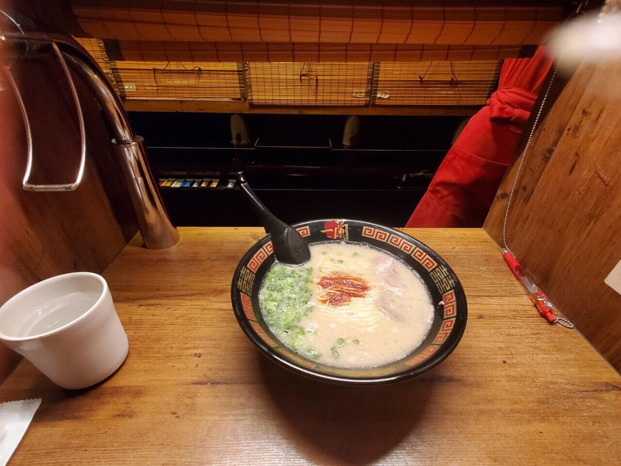 目の前のすだれ越しに提供されたラーメンを撮影したカウンター席の風景。緊張感とわくわく感が入り混じる瞬間