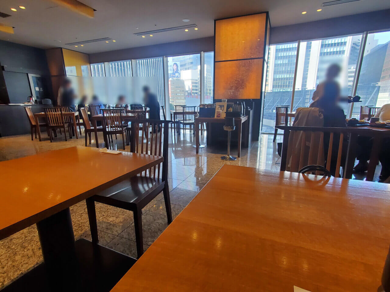 有楽町のダイナミックキッチン&バー響の店内。大きな窓と木目調のテーブルが並ぶ落ち着いた雰囲気の空間。お客さんがゆったりと食事を楽しんでいる様子。
