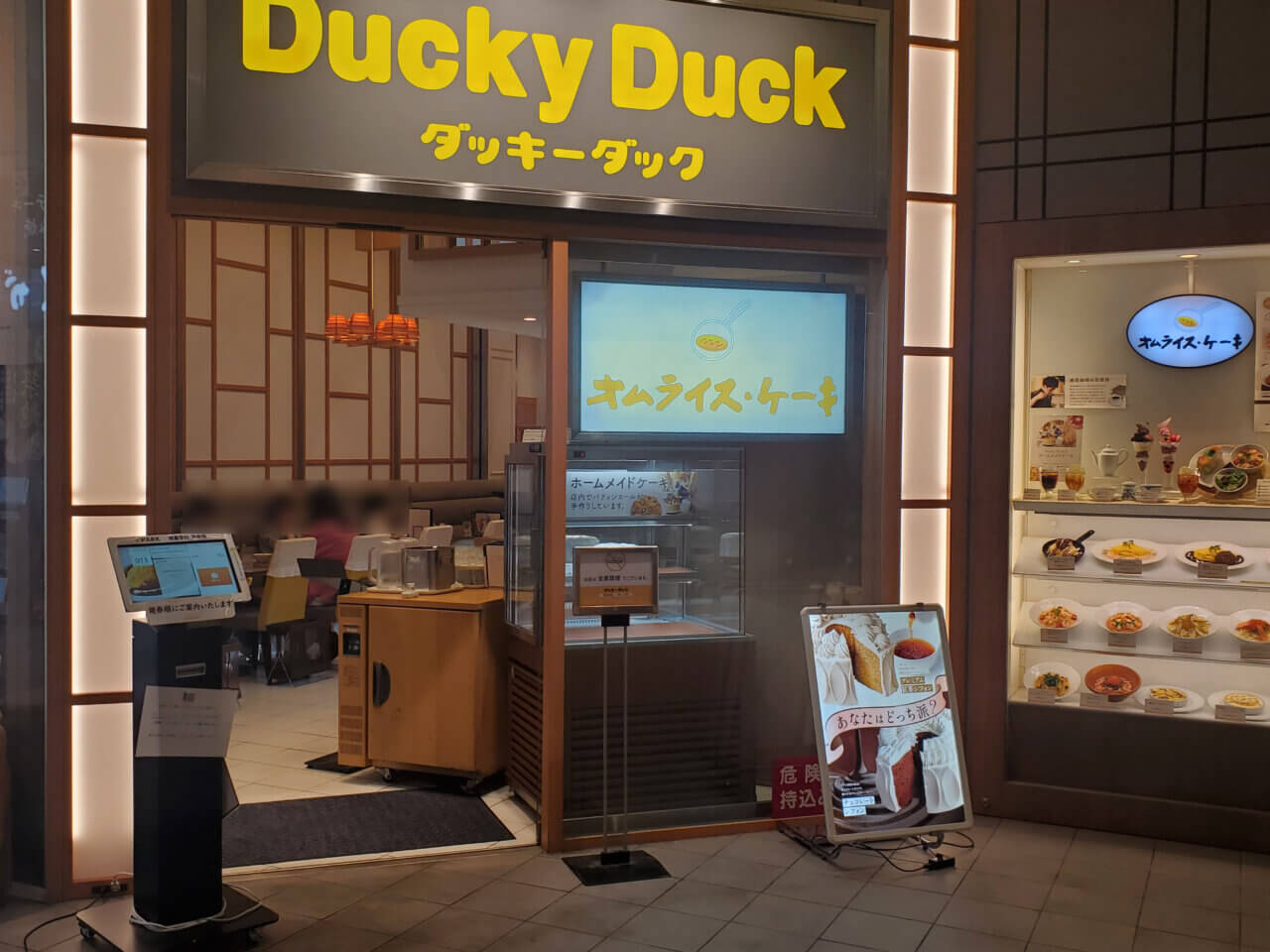 有楽町のダッキーダック店頭の写真。黄色いロゴとオムライス・ケーキの看板が目印。店内の様子も見える。